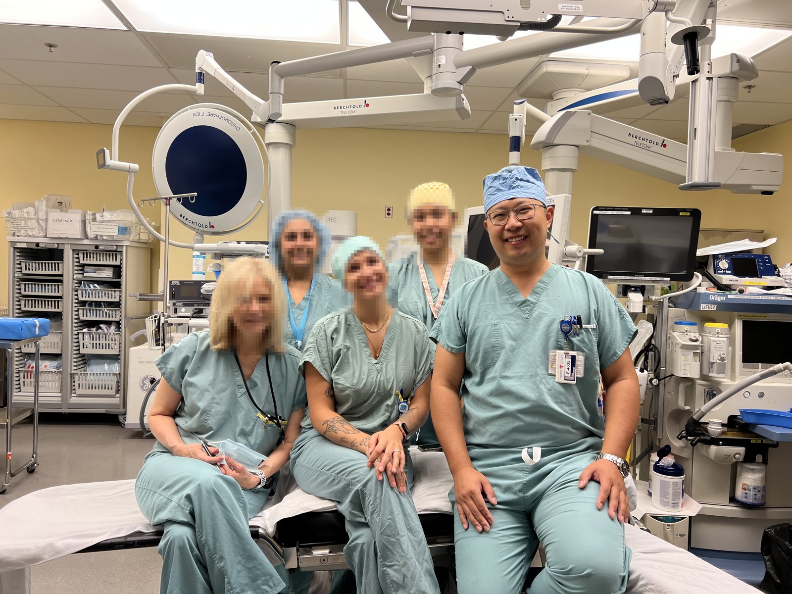 Shengbo Yu in operating-room scrubs with his team, in an operating room